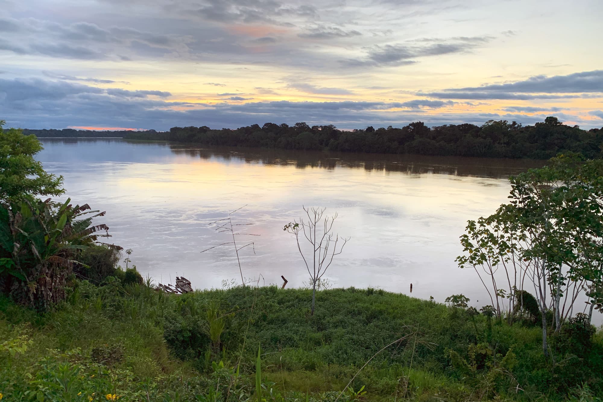 A river at sunrise or sunset, with the yellow and blue sky reflecting on the water.