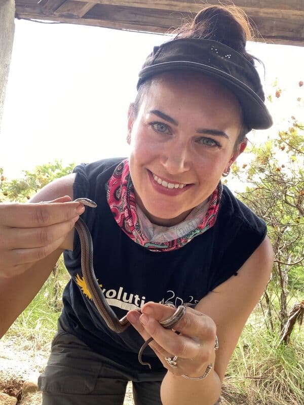 A smiling woman holding a small snake