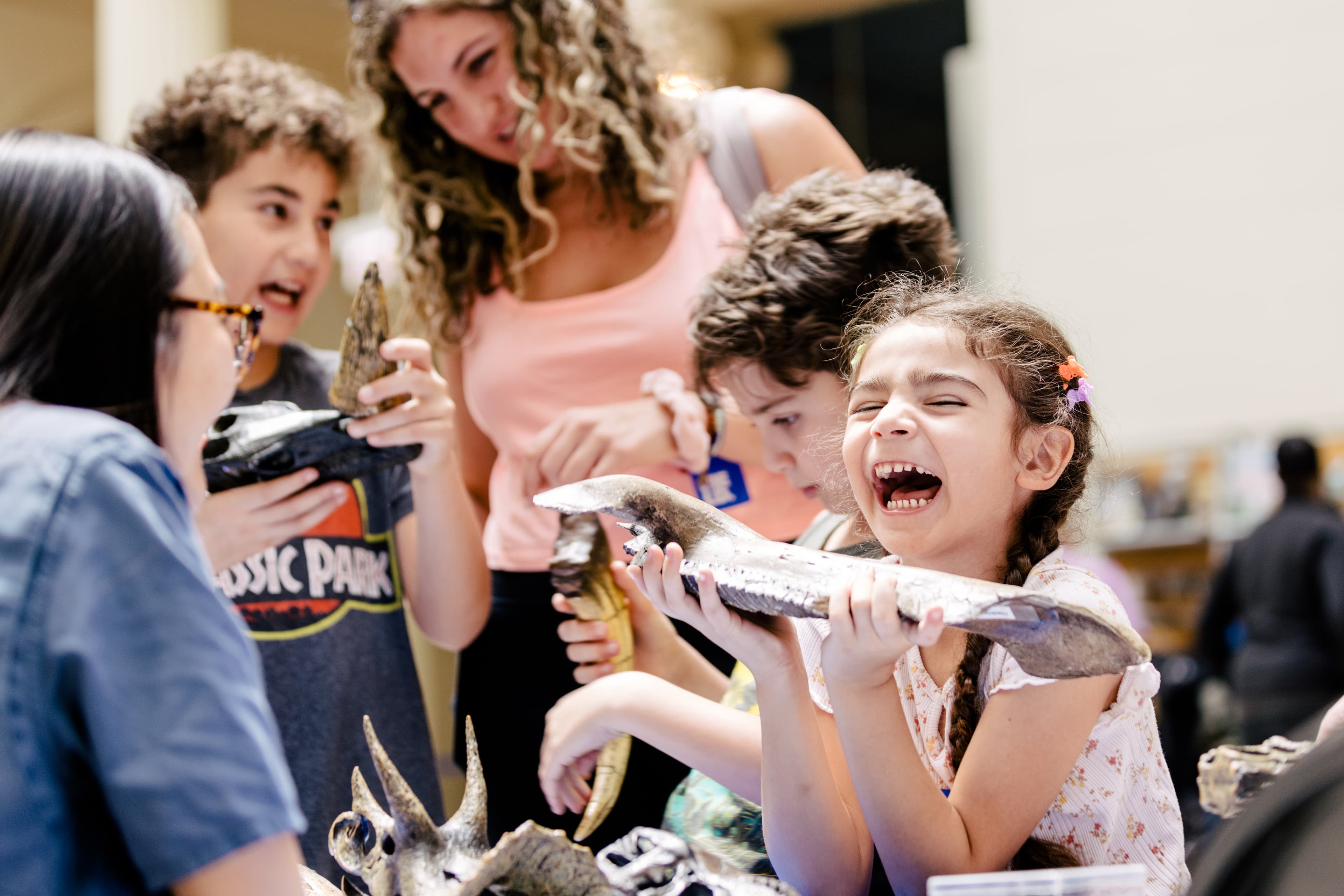 A young girl grins widely as she holds a fossil in both hands.