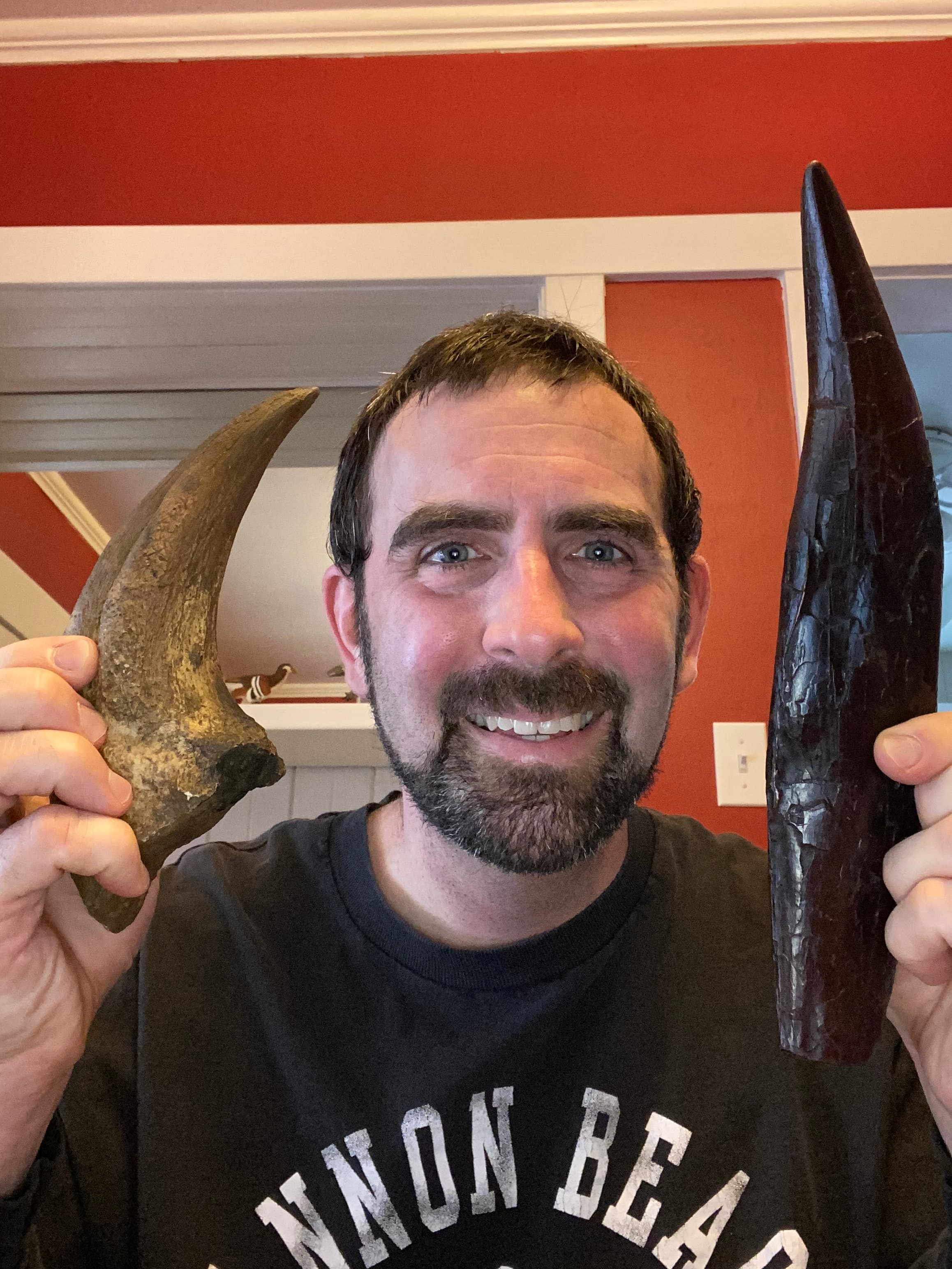 A man holding two large fossil, one on each side of his head.