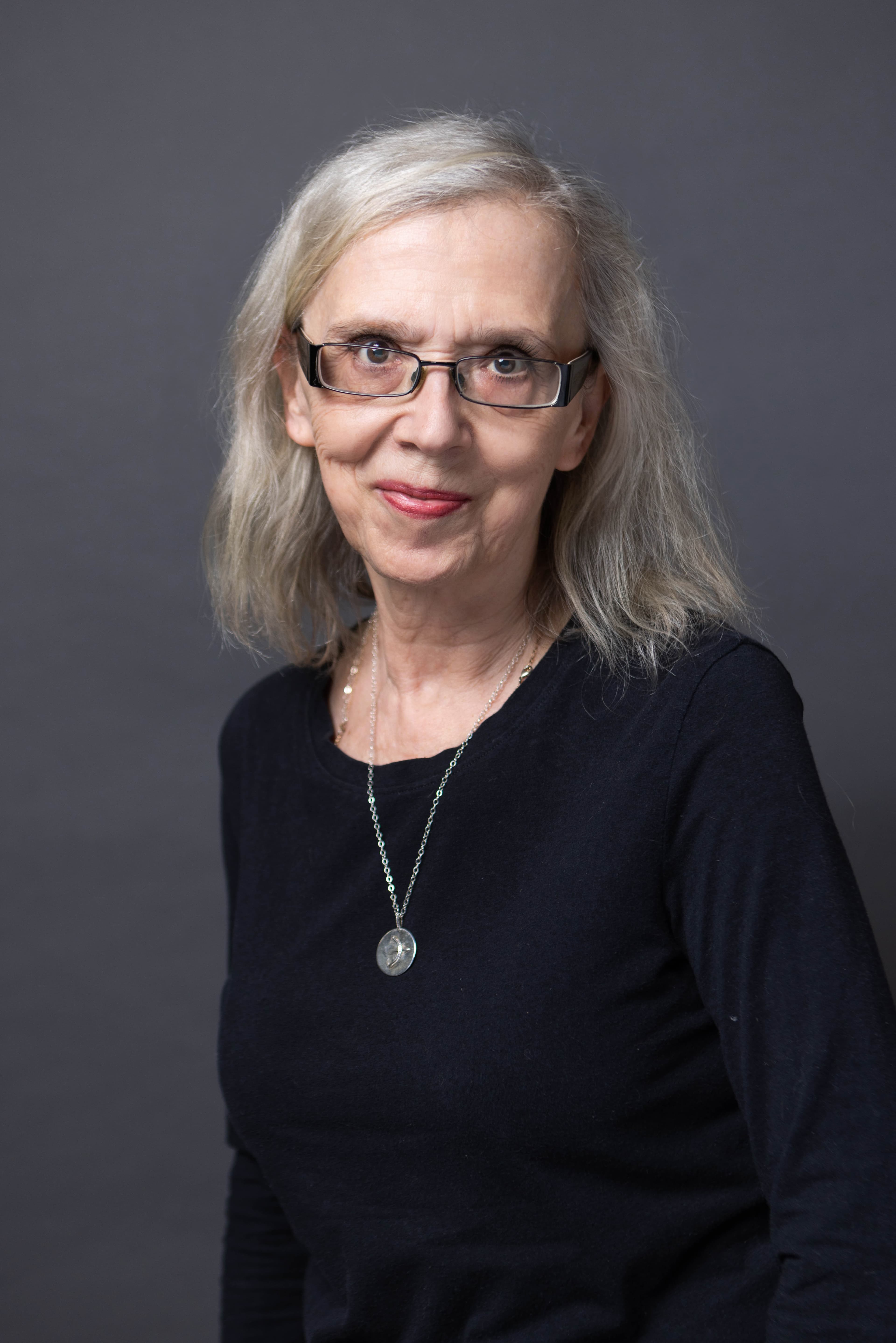 A woman wearing a black top and glasses.